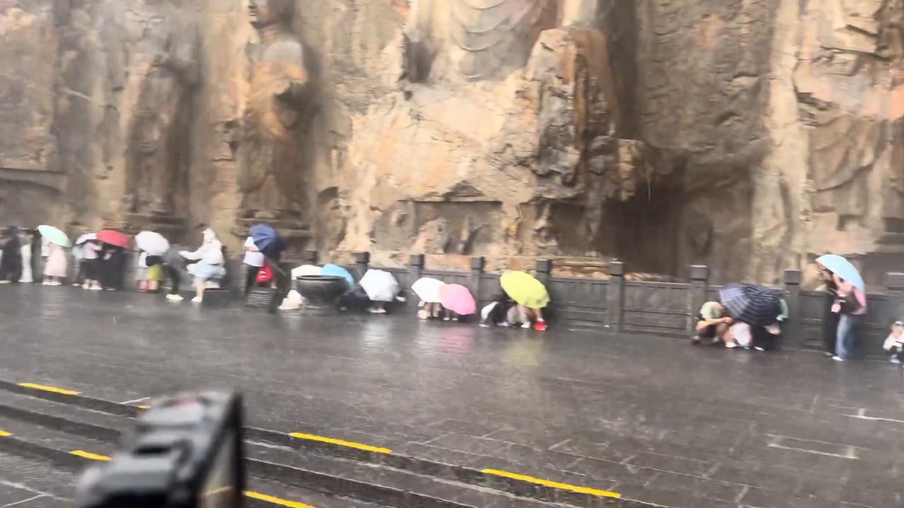 Video thumbnail for China: Tourists shelter under buddha statues as torrential rain hits Longmen Grottoes in China.