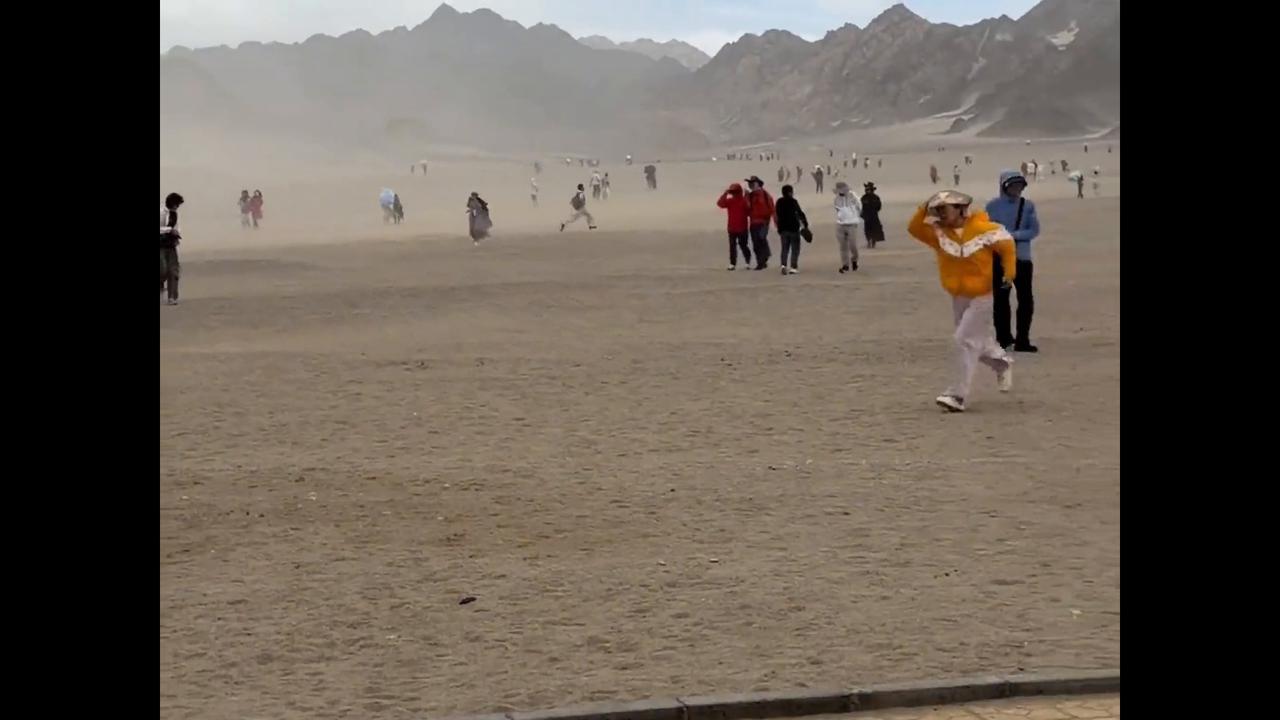 Video thumbnail for China: Chinese tourist follows windblown umbrella running across desert sands.