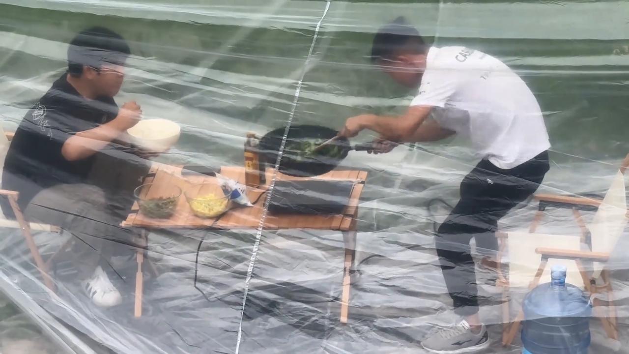 Video thumbnail for China: Chinese men camp with car air conditioning under plastic cover.