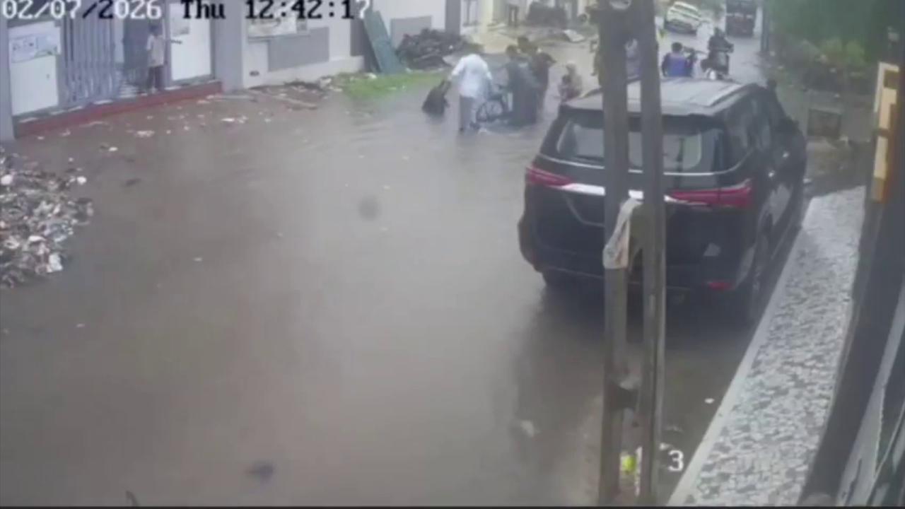 Video thumbnail for India: Heavy rain exposes civic lapses as man carrying bicycle falls into waterlogged pothole in India.
