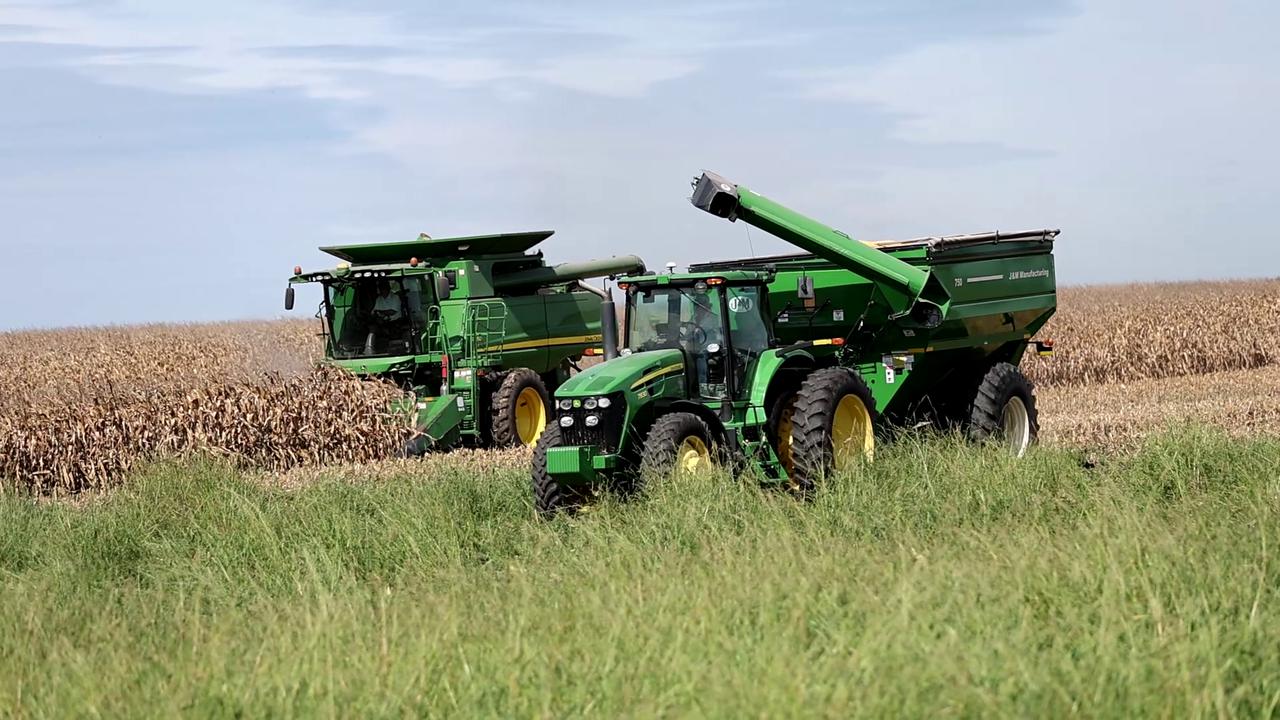 Video thumbnail for US: John Deere Combine Unloading Harvested Corn into Tractor-Drawn Grain Cart.