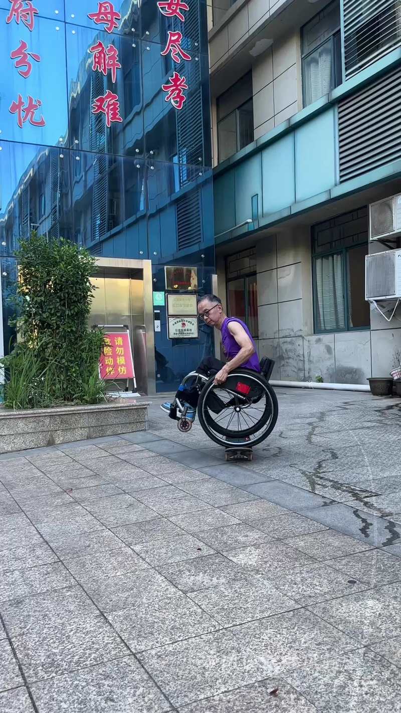 Video thumbnail for Wheelchair Rider Balances on Skateboard through Courtyard