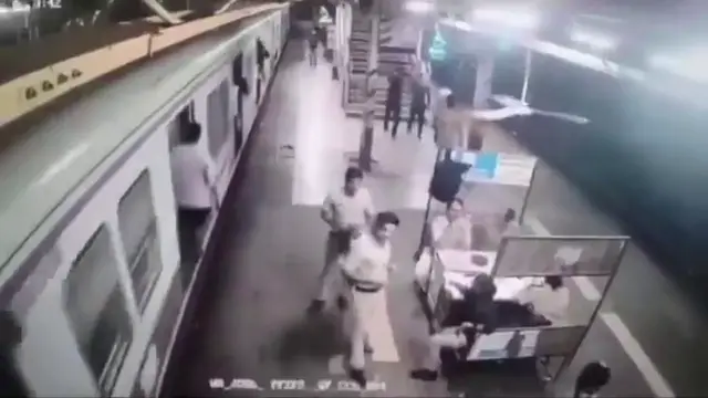 Video thumbnail for India: Young man loses balance while boarding moving local train as official rush to pull him from platform gap.