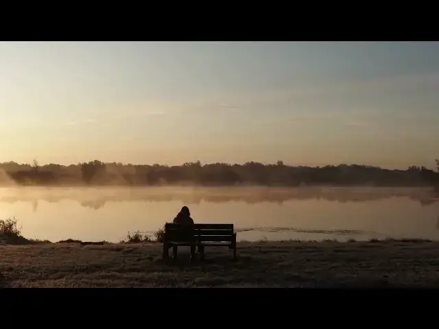Video thumbnail for Man sitting on bench behind of a Lake