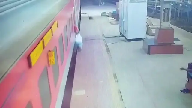 Video thumbnail for India: Quick-thinking official saves passenger as slip sends him beneath moving train during boarding.