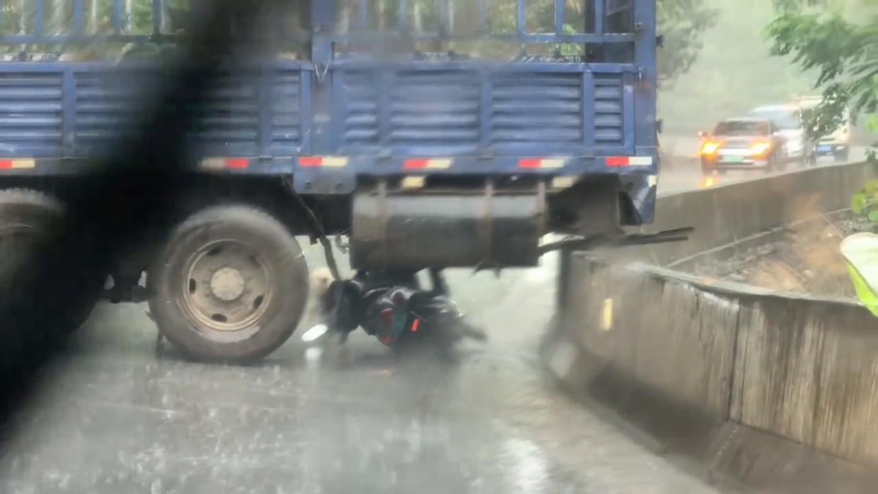 Video thumbnail for China: Chinese motorcyclist squeezes under truck blocking mountain road.