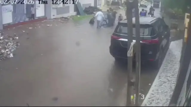 Video thumbnail for India: Heavy rain exposes civic lapses as man carrying bicycle falls into waterlogged pothole in India.
